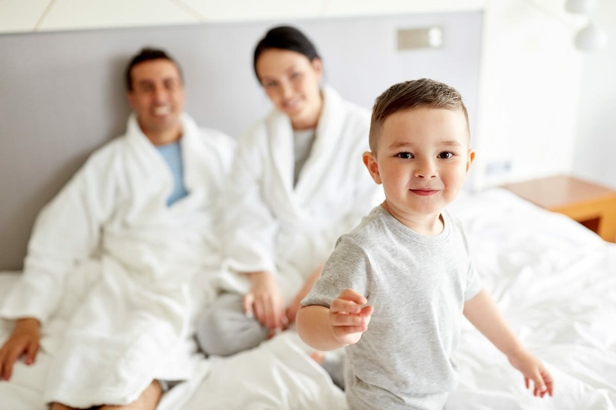Mother and father in bath robes with happy child in a hotel room